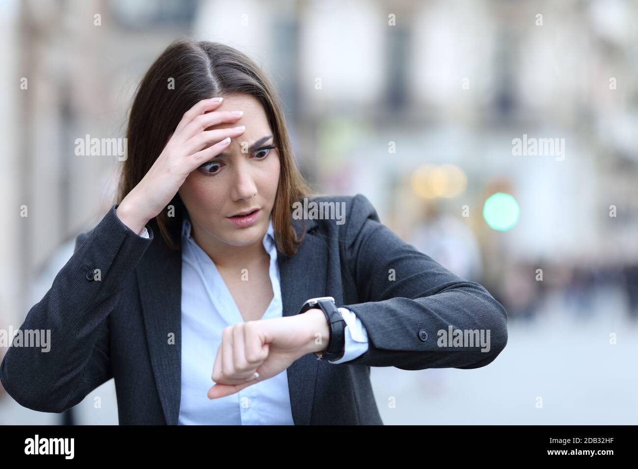 Front view of a worried business woman checking time on her smart watch ...