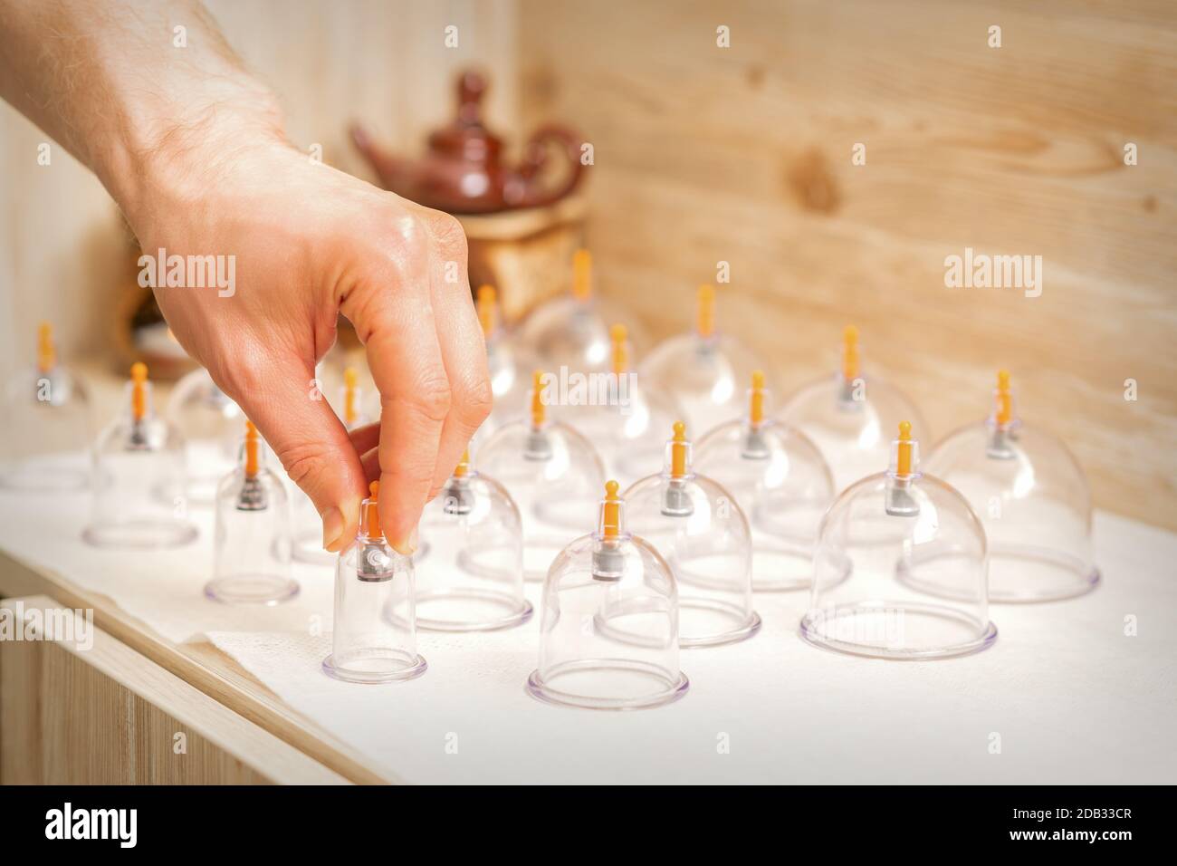 Masseur takes vacuum massage glass jars of traditional Chinese cupping therapy from table in spa