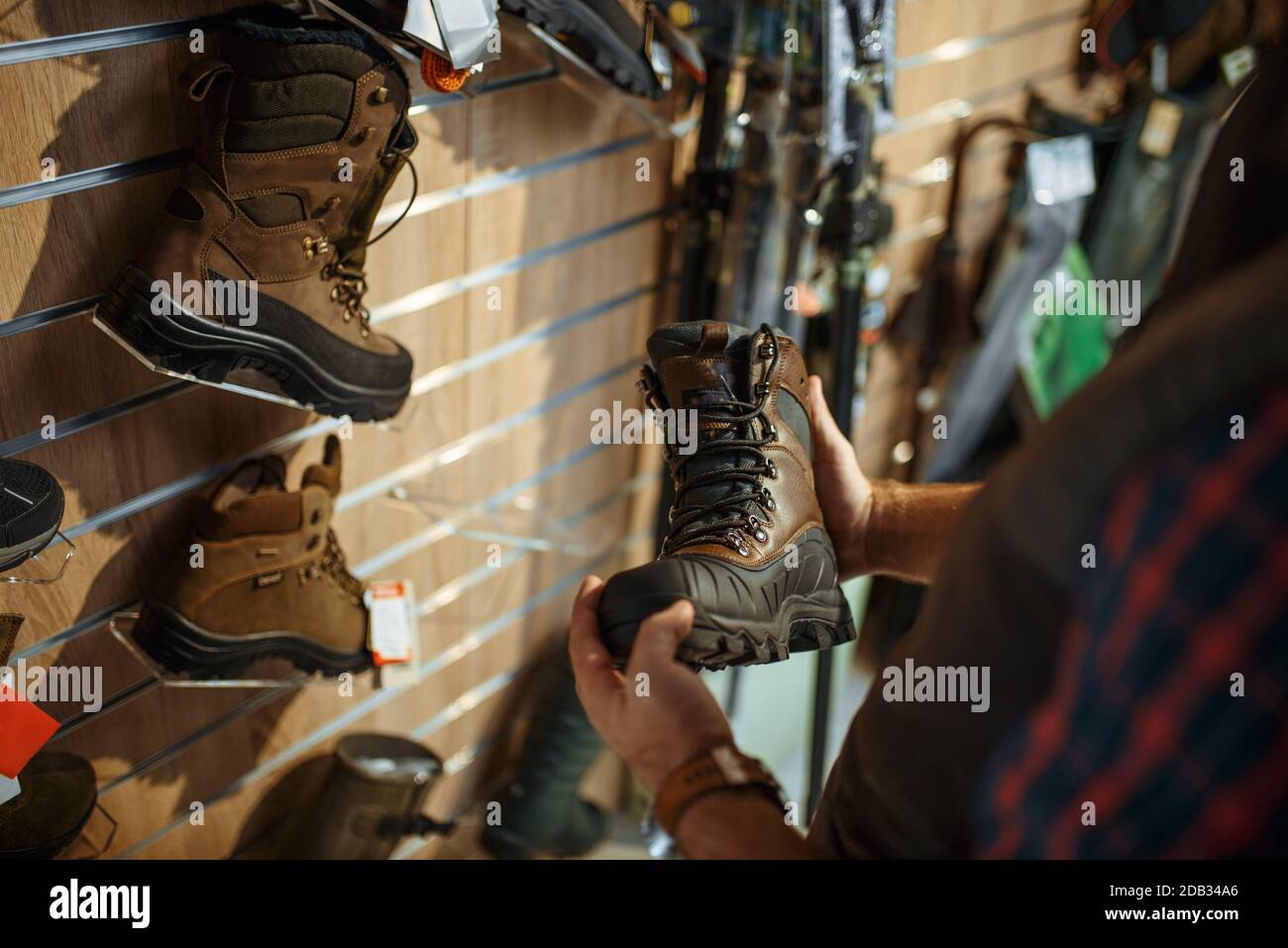 Man choosing boots for hunters at showcase in gun shop. Euqipment and ...