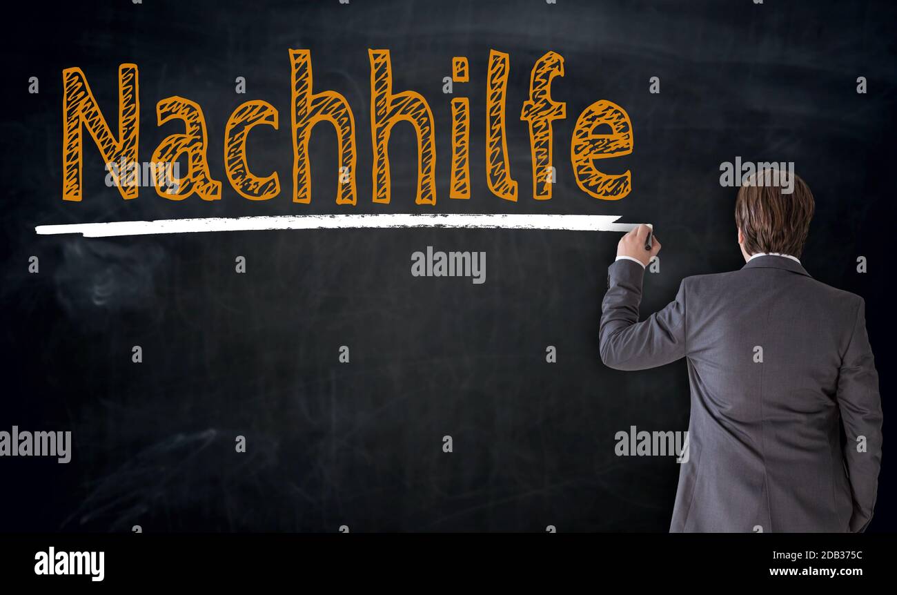 Businessman writes Nachhilfe (in german private turoring) on blackboard concept. Stock Photo