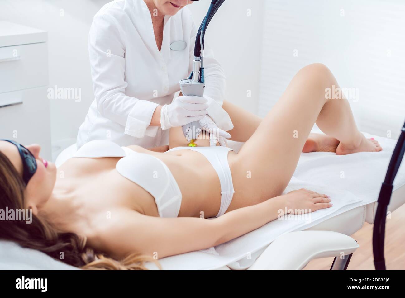 therapist using painless laser technology for the hair removal in the bikini zone of a female client in a modern beauty salon Stock Photo