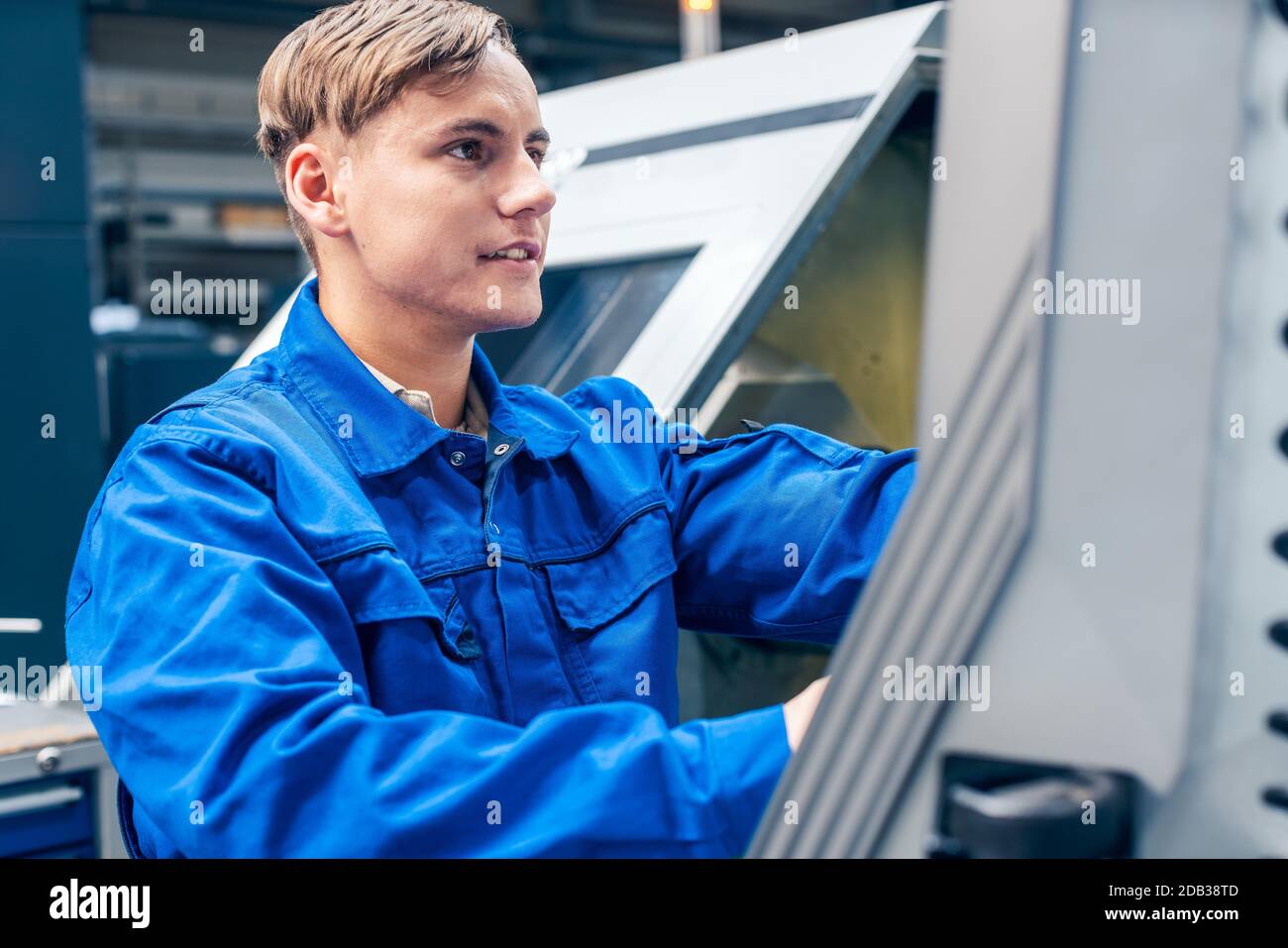 Young male worker programming lathe machine in factory Stock Photo