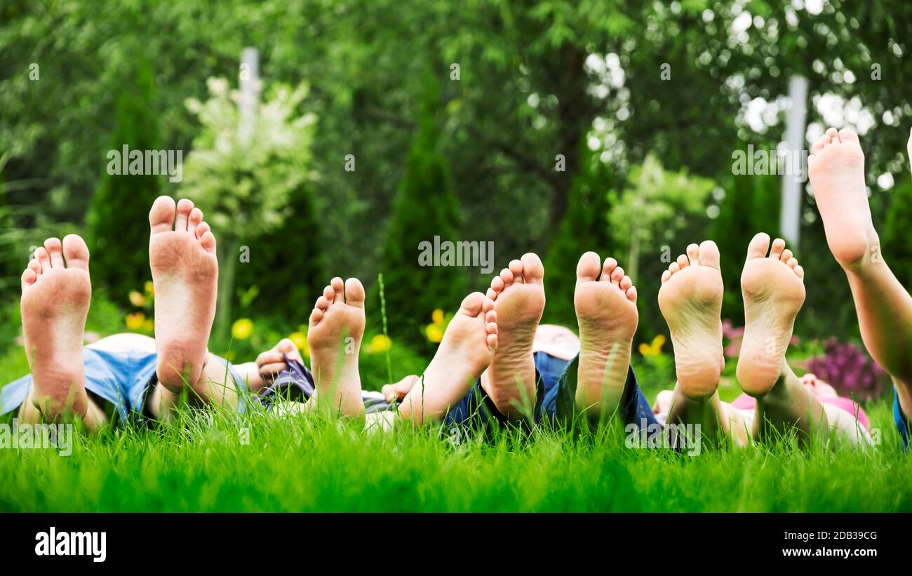 Family relaxing on green grass, barefoot laying down and looking into the sky Stock Photo