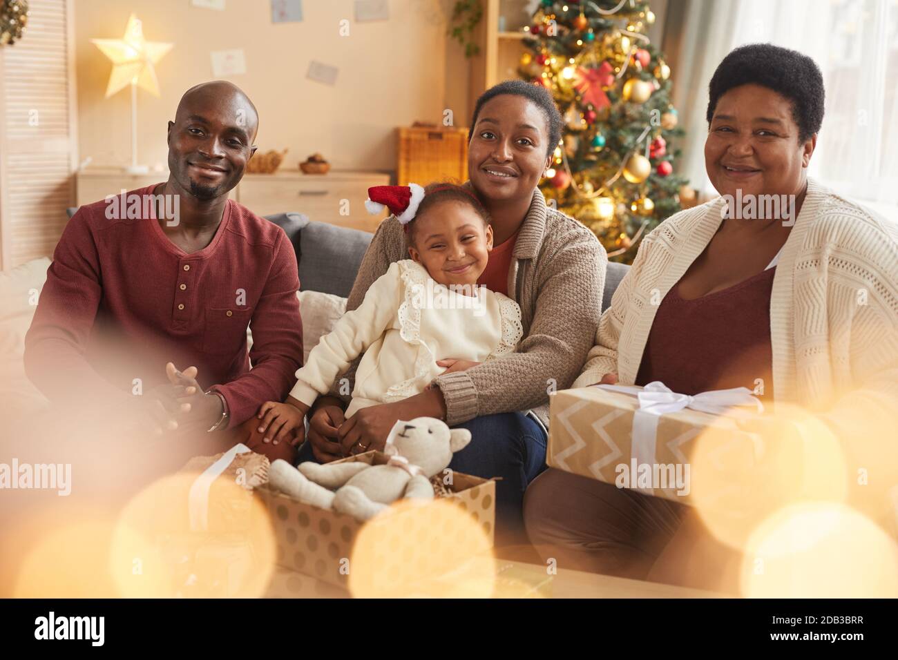 Magical portrait of happy African-American family looking at camera while enjoying Christmas at home Stock Photo