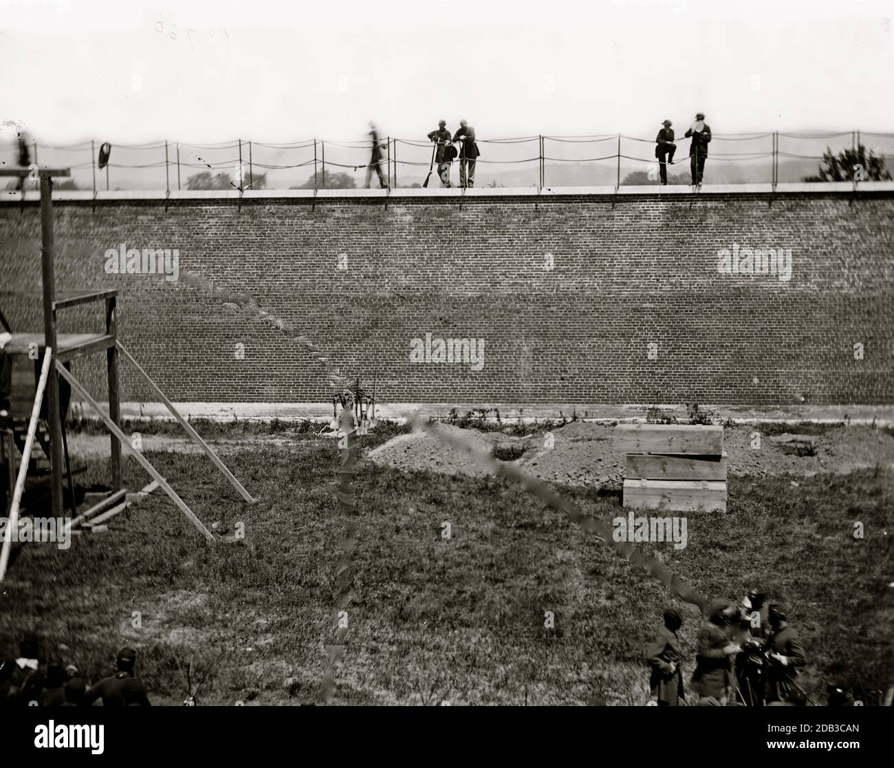 Washington, D.C. Coffins and open graves ready for the conspirators' bodies at right of scaffold. Stock Photo