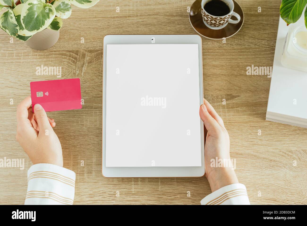 Vertical tablet mockup with a woman holding a credit card in her home. Blank screen to insert design. E-commerce concept Stock Photo