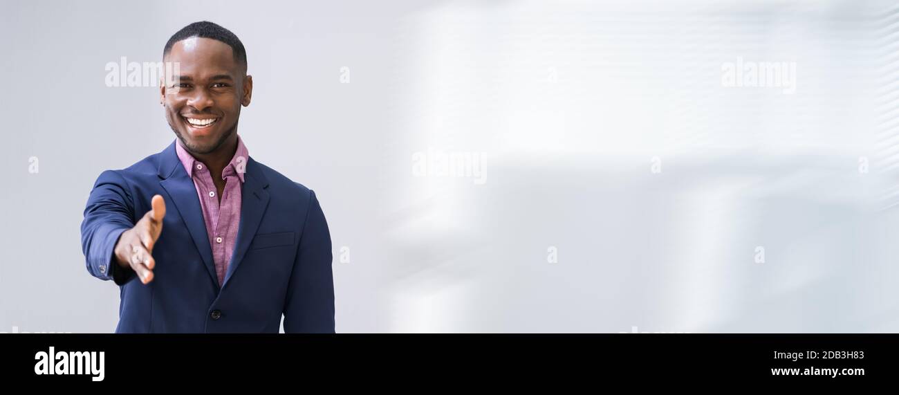 Happy Young Businessman Extending Hand To Shake Stock Photo