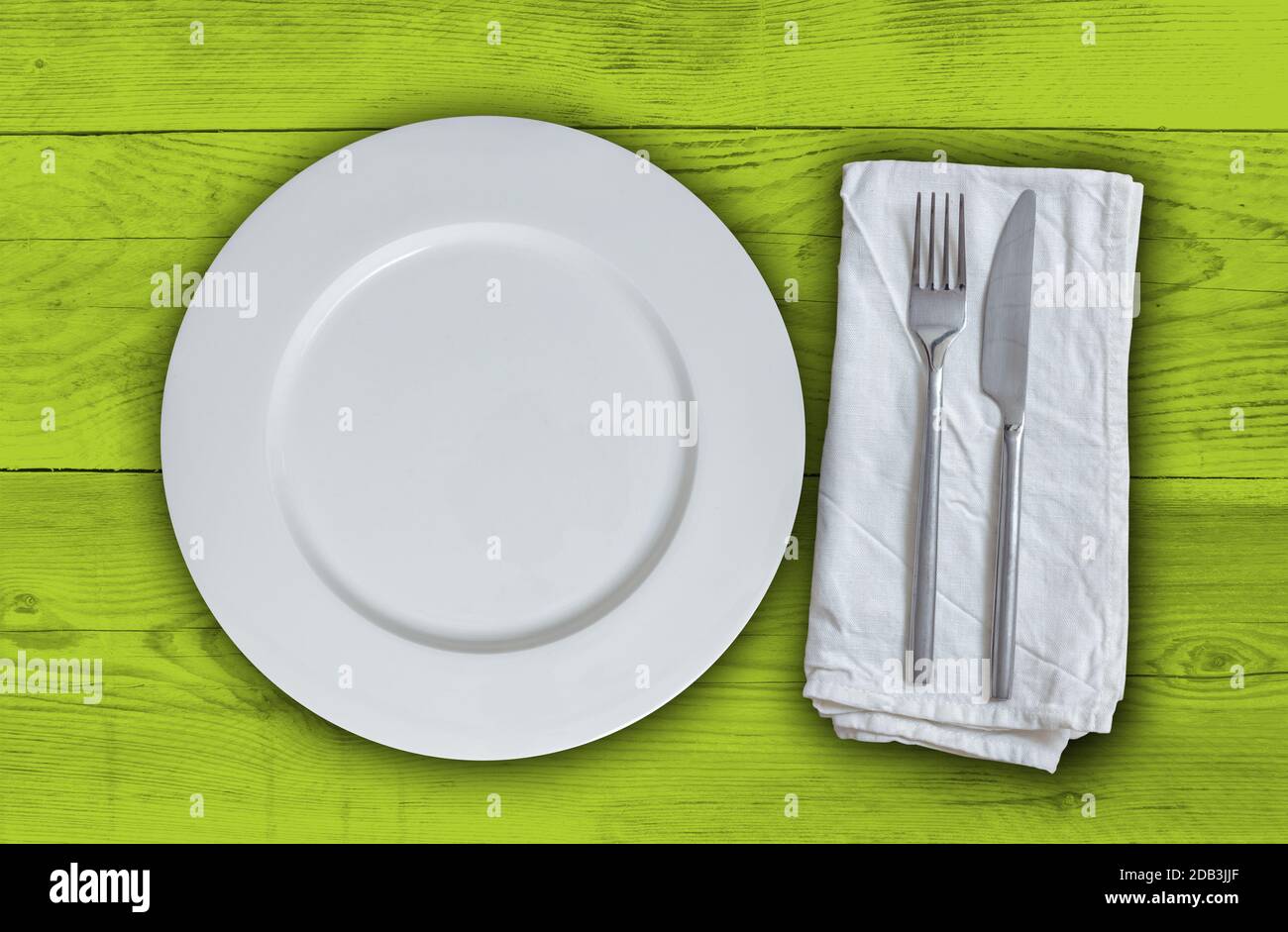 Empty plate with cutlery on light green vintage wood. Stock Photo