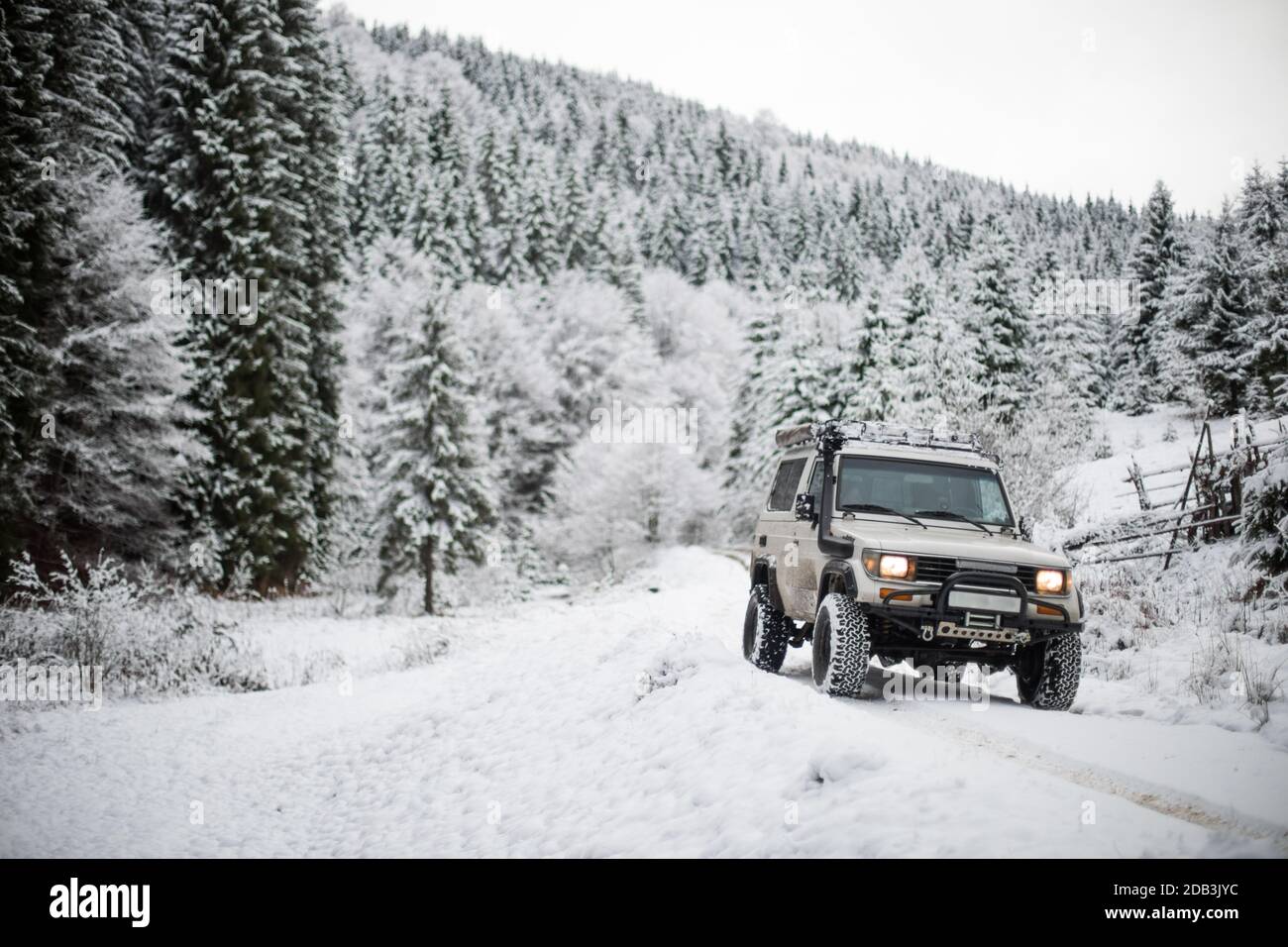 Color image of an off road car, driving on a track in a snow covered forest. Stock Photo