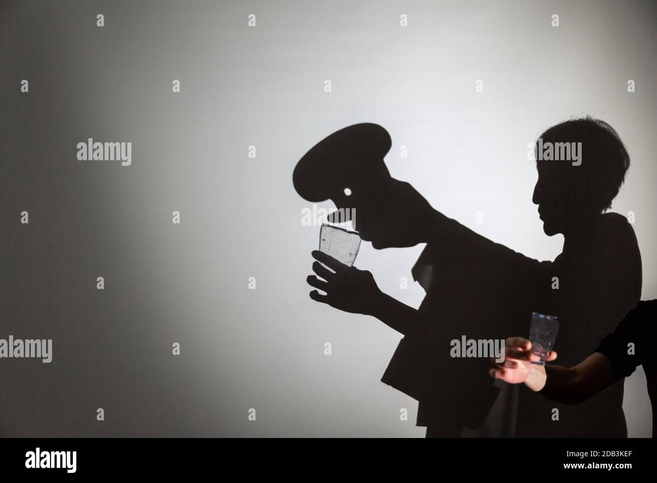 play shadow projected on a white screen. the person's hands shape a cook drinking from a glass Stock Photo