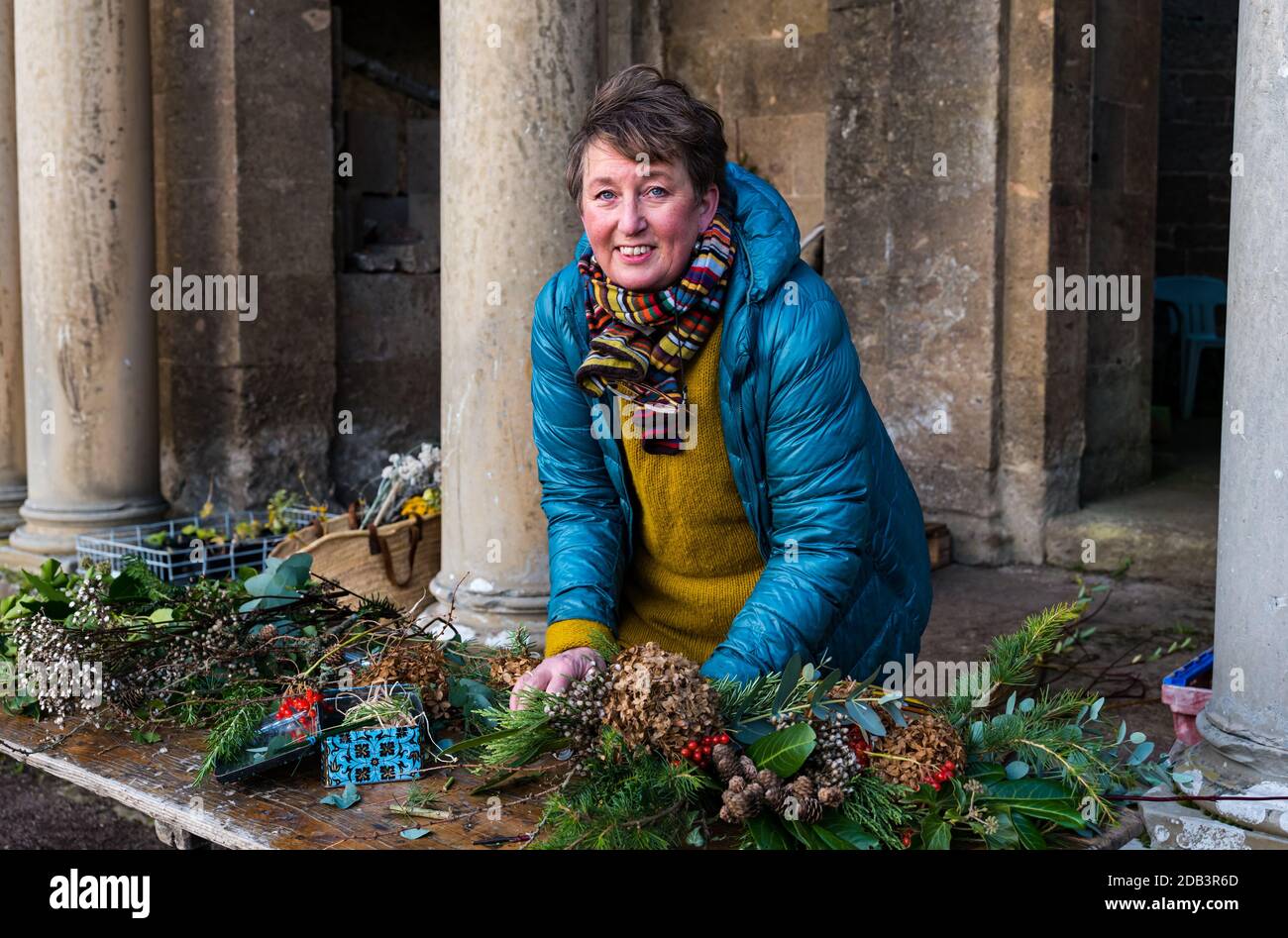 Haddington, East Lothian, Scotland, UK, Flowersmith prepares for Christmas:  Ruth Alder, a flowersmith, weaves willow into wreaths to decorate for Christmas using foliage and flowers from Amisfield Walled Garden where she is a volunteer. Amisfield Walled garden is an 18th century garden managed by the Amisfield Preservation Trust and is free to visit all year round. Pictured: Ruth attaches flowers and foliage gathered from the walled garden Stock Photo