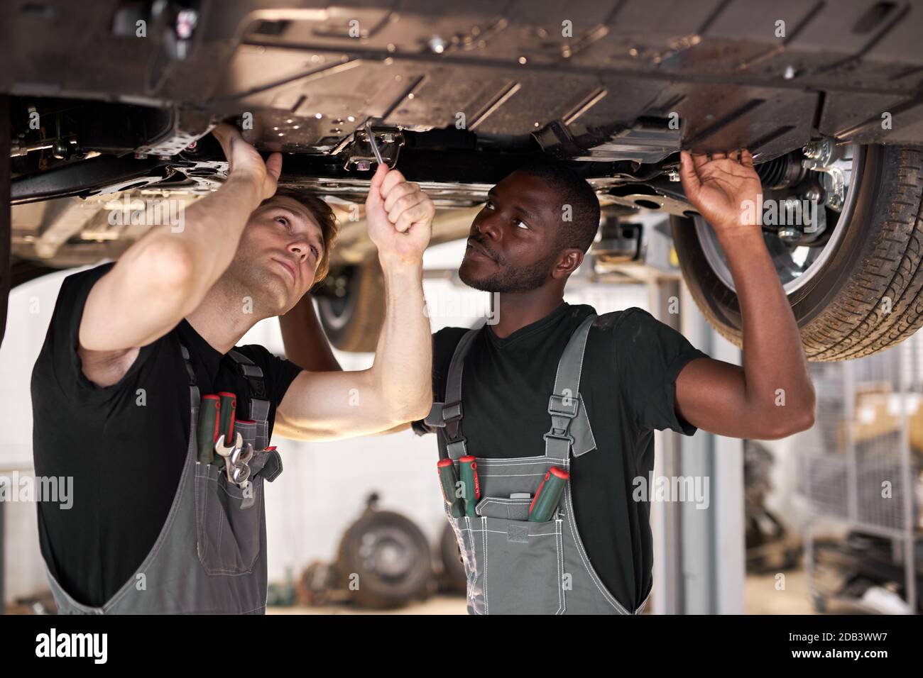 two friendly professional auto mechanic during work, they are ...