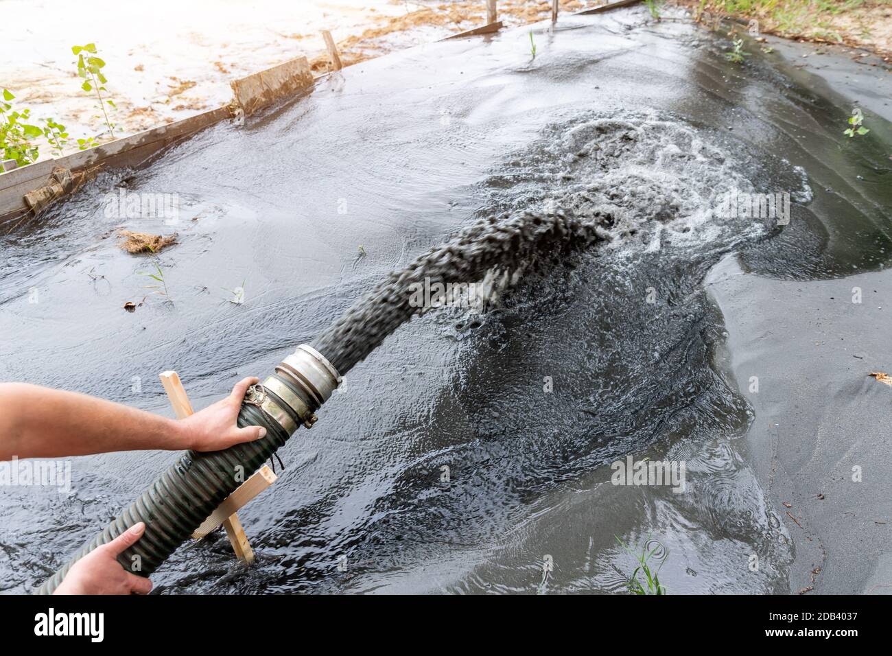 Engeneer hold pipe of power pump machine pouring mud sludge waste water