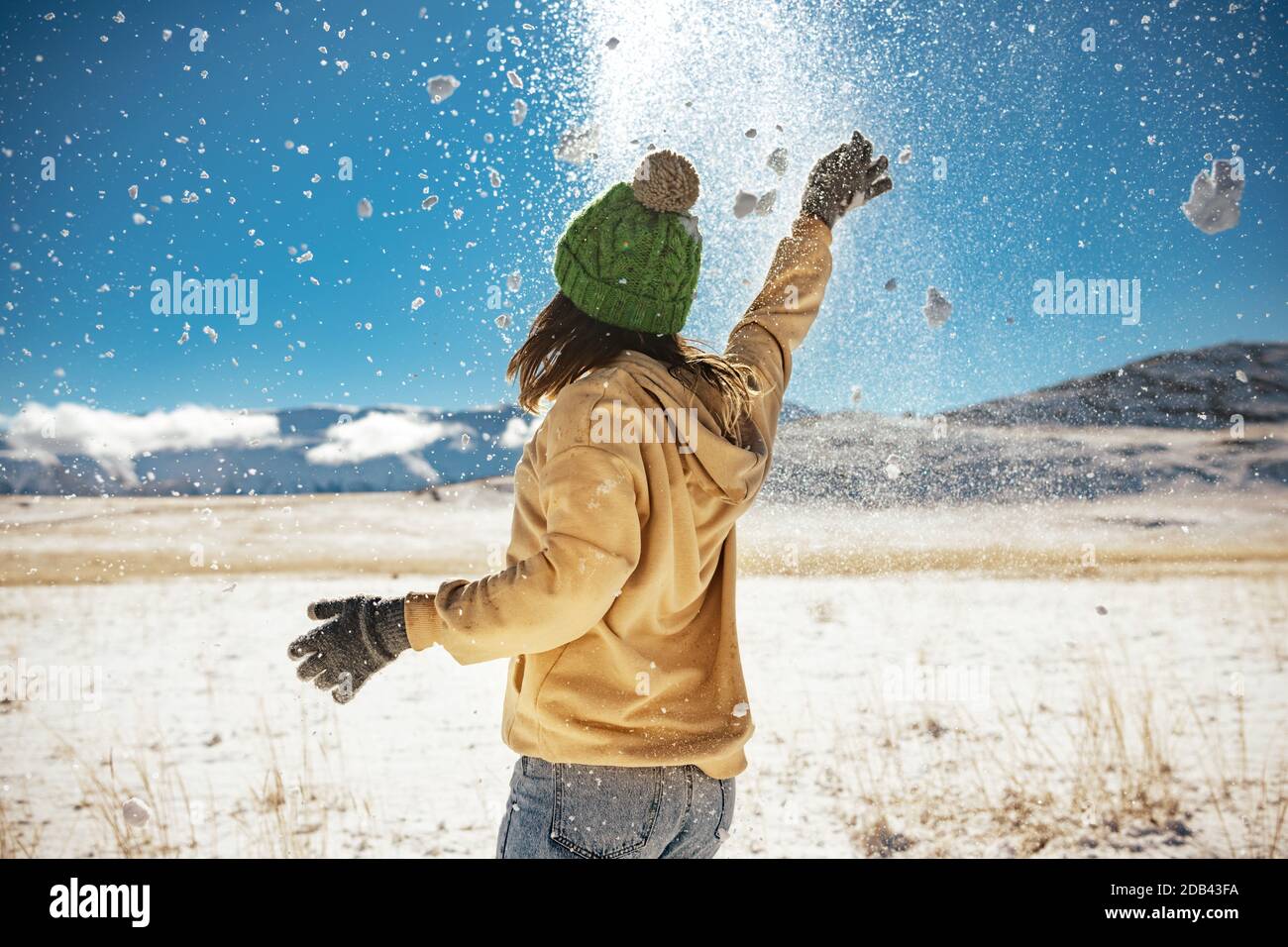 Happy girl is having fun and tossing snow in mountains. First snow concept Stock Photo