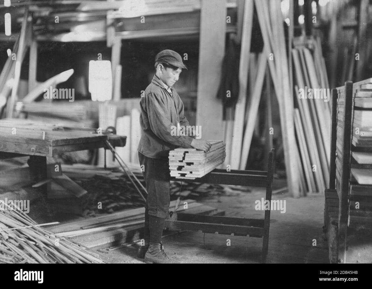 Boy probably about 13 years old, tying strips which he has taken away from the planer. Schultze Waltum Co., Planing Mill. Stock Photo
