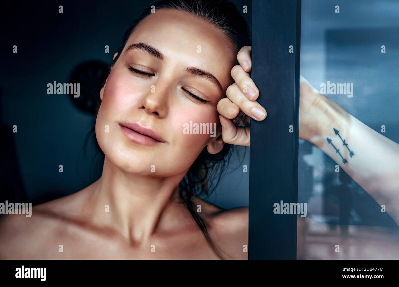 Portrait of a beautiful woman in a dreamy mood with closed eyes standing near the window at home, genuine beauty of a young female Stock Photo