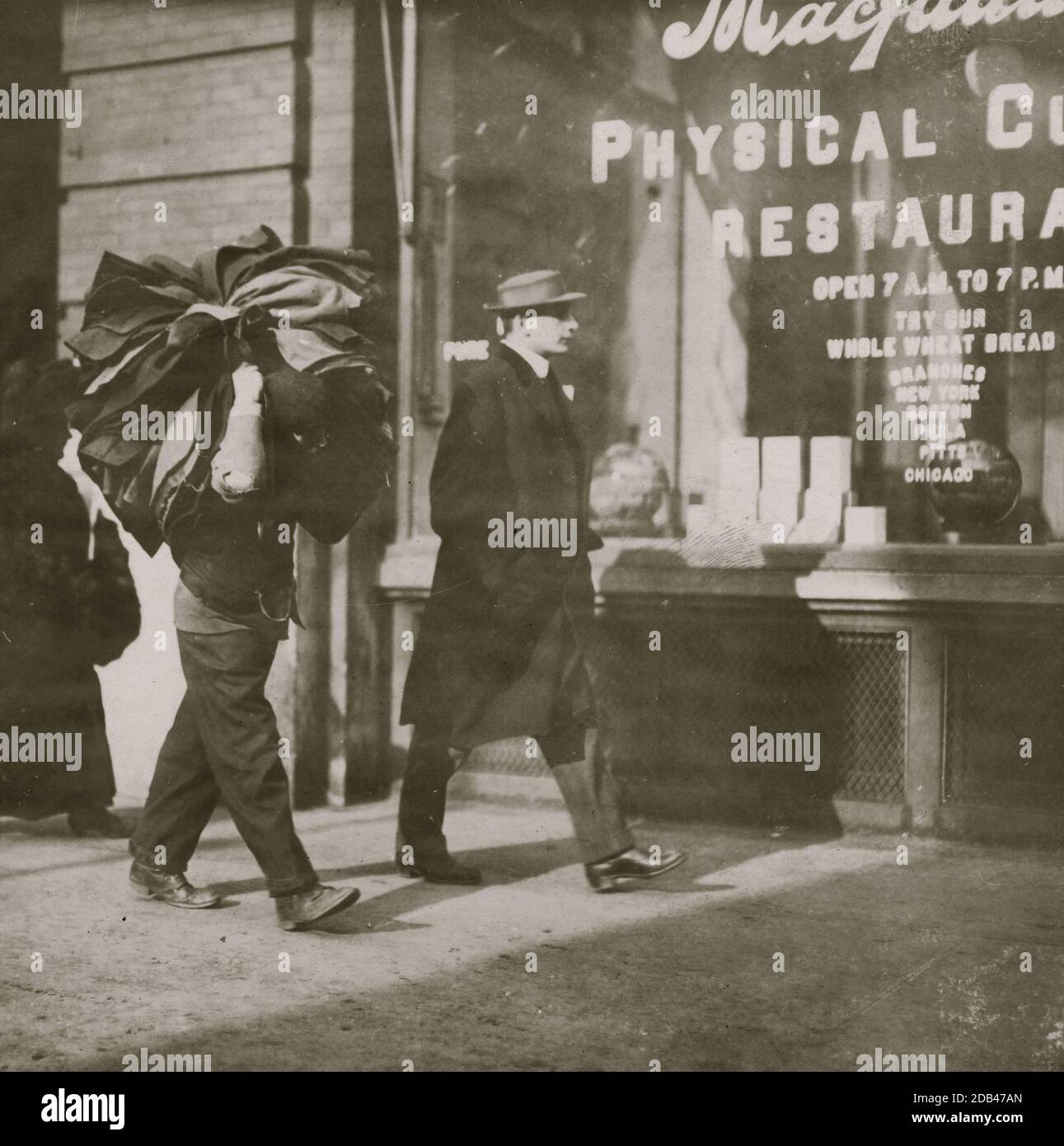 Man carrying bundle of garments. Bleeker St., N.Y. . Stock Photo