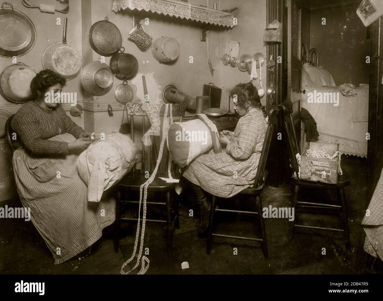 Mrs. Palontona and 13 year old daughter, Michaeline, working on 'Pillow-lace' in dirty kitchen of their tenement home, 213 E. 111th Street, 3rd floor. They were both very illiterate. Mother is making fancy lace and girl sold me the piece she worked on.. Stock Photo