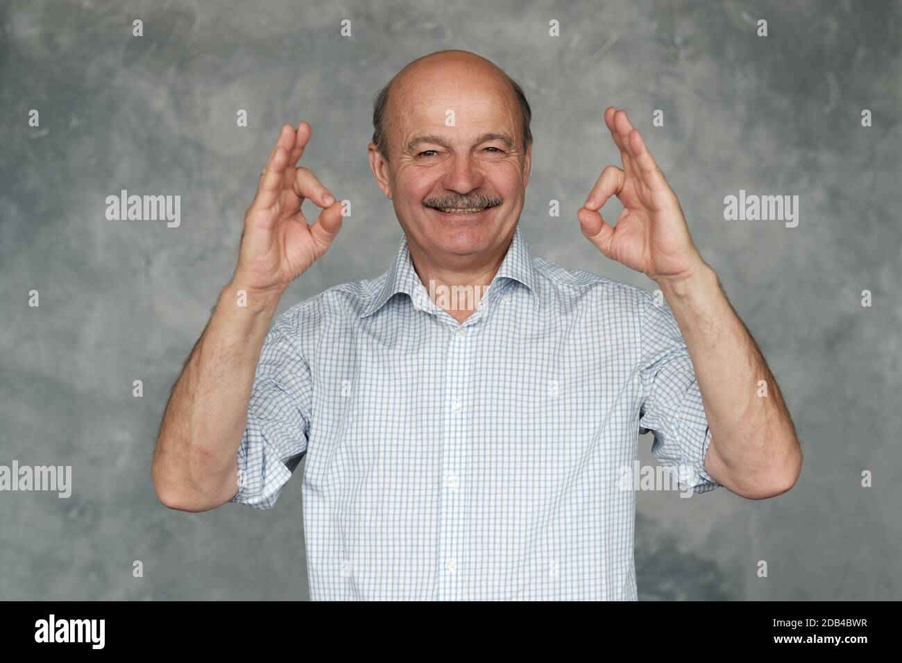 Senior man with mustache showing OK sign approving your choice Stock Photo
