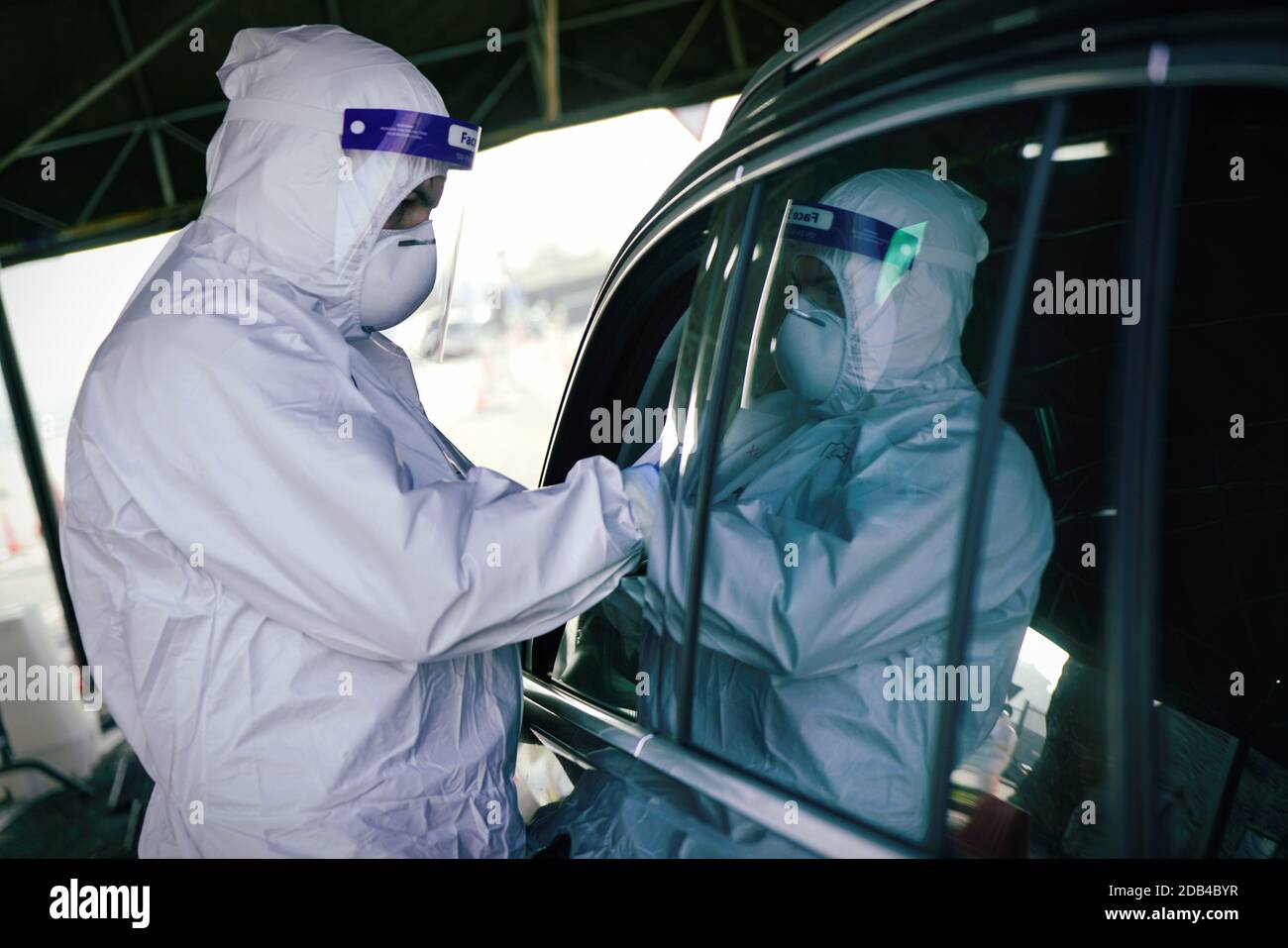 Medical worker in PPE performing nasal & throat swab on person in vehicle through car window,COVID-19 mobile testing centre. Turin, Italy - November 2 Stock Photo