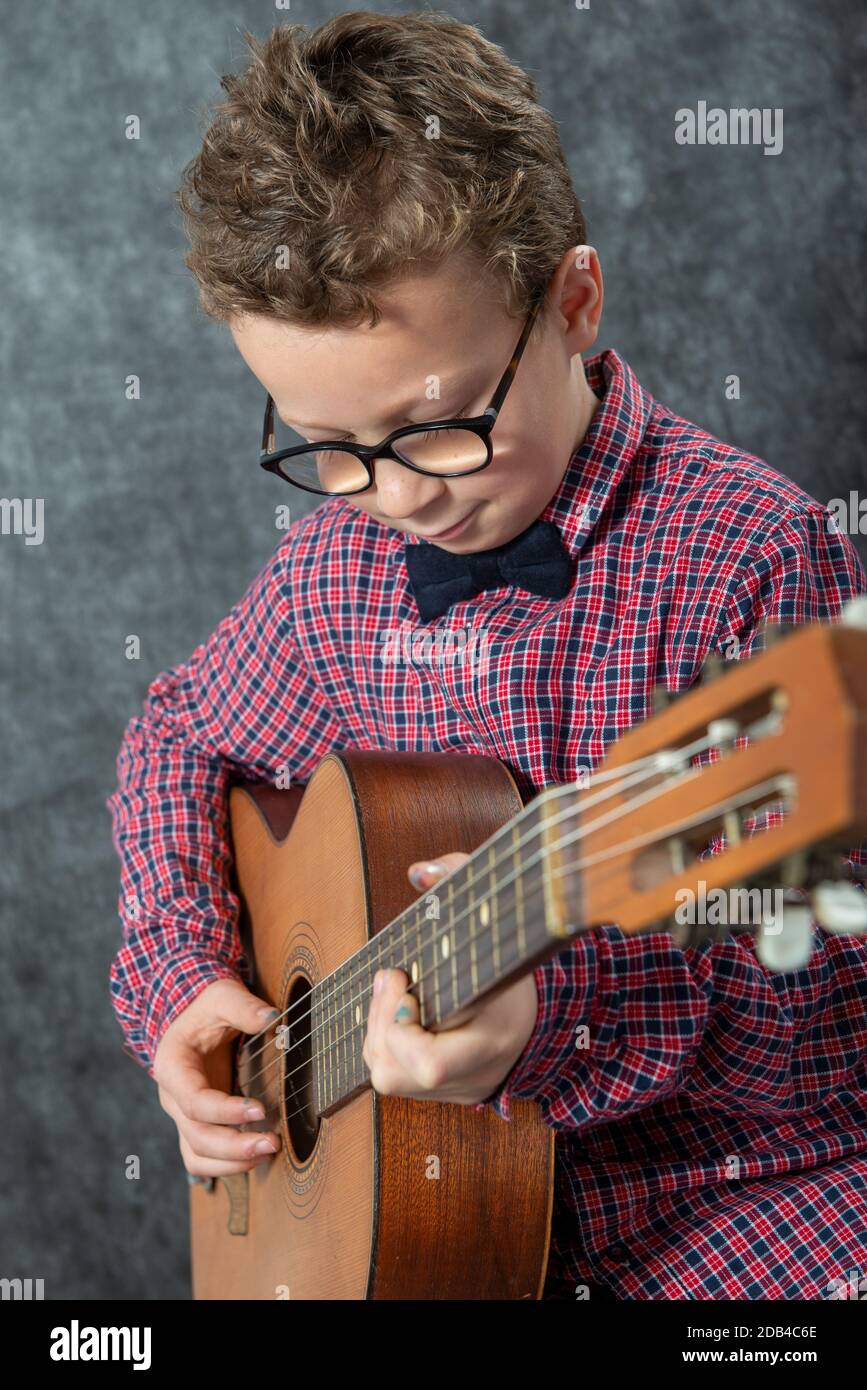 boy with a checkered shirt playing on acoustic guitar Stock Photo