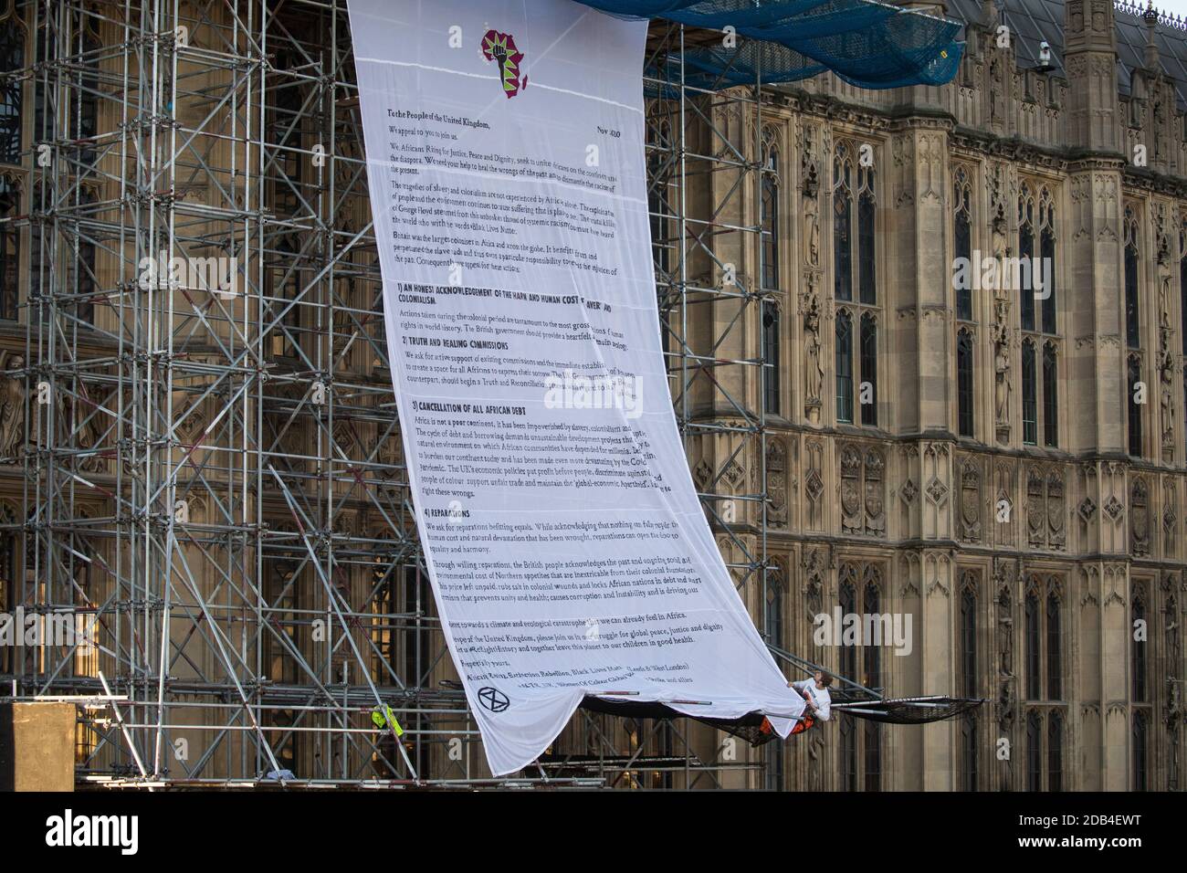 London, UK. 12th November, 2020. Activists from the group Action for Climate Truth and Reparations (ACTR) hang an open letter to the UK people from Africans Rising For Justice, Peace and Dignity from the Houses of Parliament. The letter, which launches Africans Rising’s ReRight History campaign, contains a plea to the UK people to start making amends for the harm caused by slavery and colonialism. Credit: Mark Kerrison/Alamy Live News Stock Photo