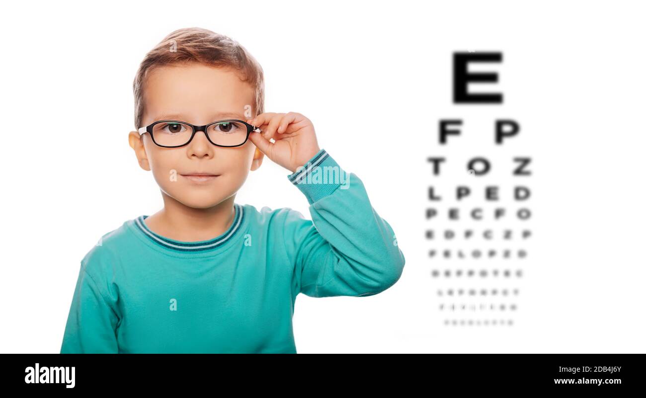 Cute boy checks vision in glasses, over eye chart. Vision correction for children Stock Photo