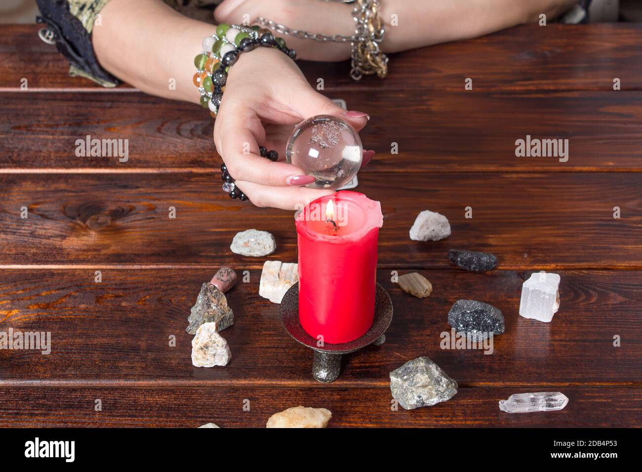 Fortune teller predicts fate using a magic ball, stones and a lit