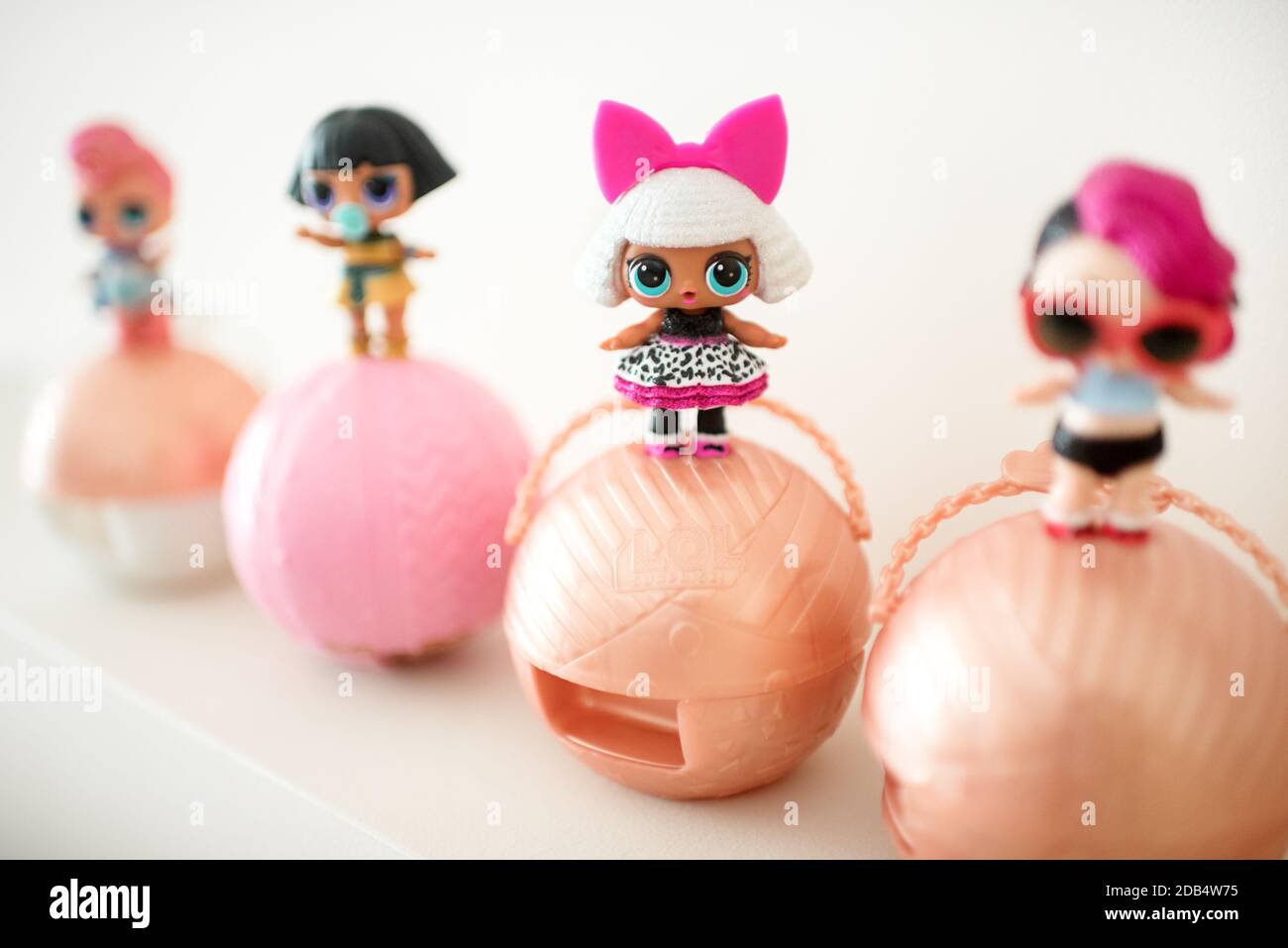 Row of cute different little L.O.L. baby dolls standing on top of their ball packaging showing different fashion accessories arranged in a diagonal ro Stock Photo