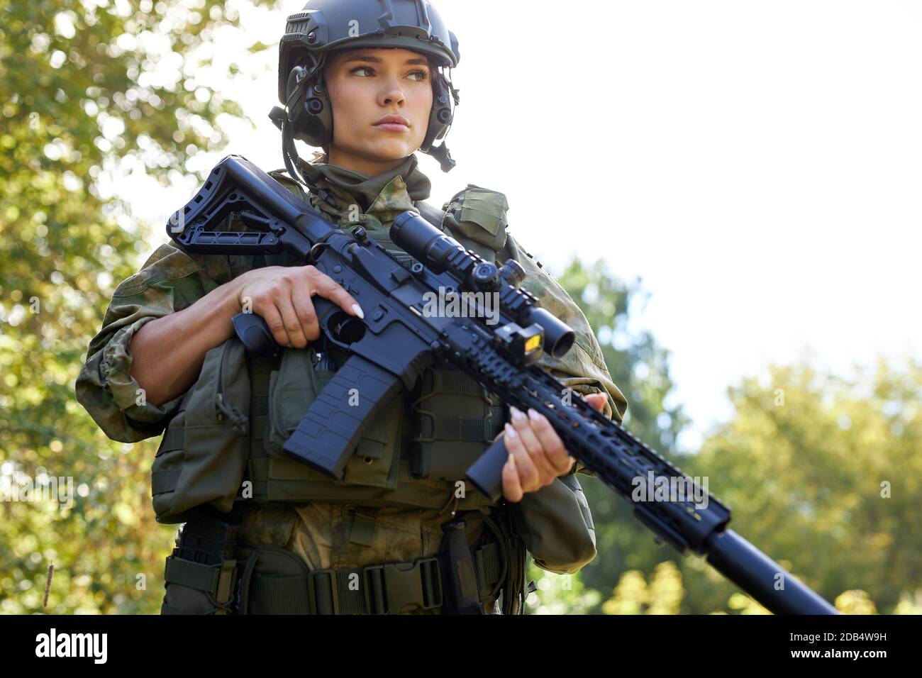 brave caucasian woman is engaged in hunting weapon gun or rifle, wearing military suit. target shot. female hunter in wild forest, nature. successful hunt. hunting sport concept Stock Photo
