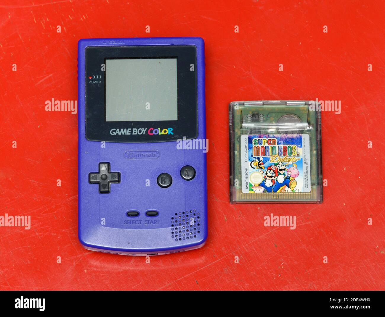 Vintage blue Game Boy by Nintendo with Super Mario Bros game lying alongside in a flat lay still life on a colorful red background in an entertainment Stock Photo