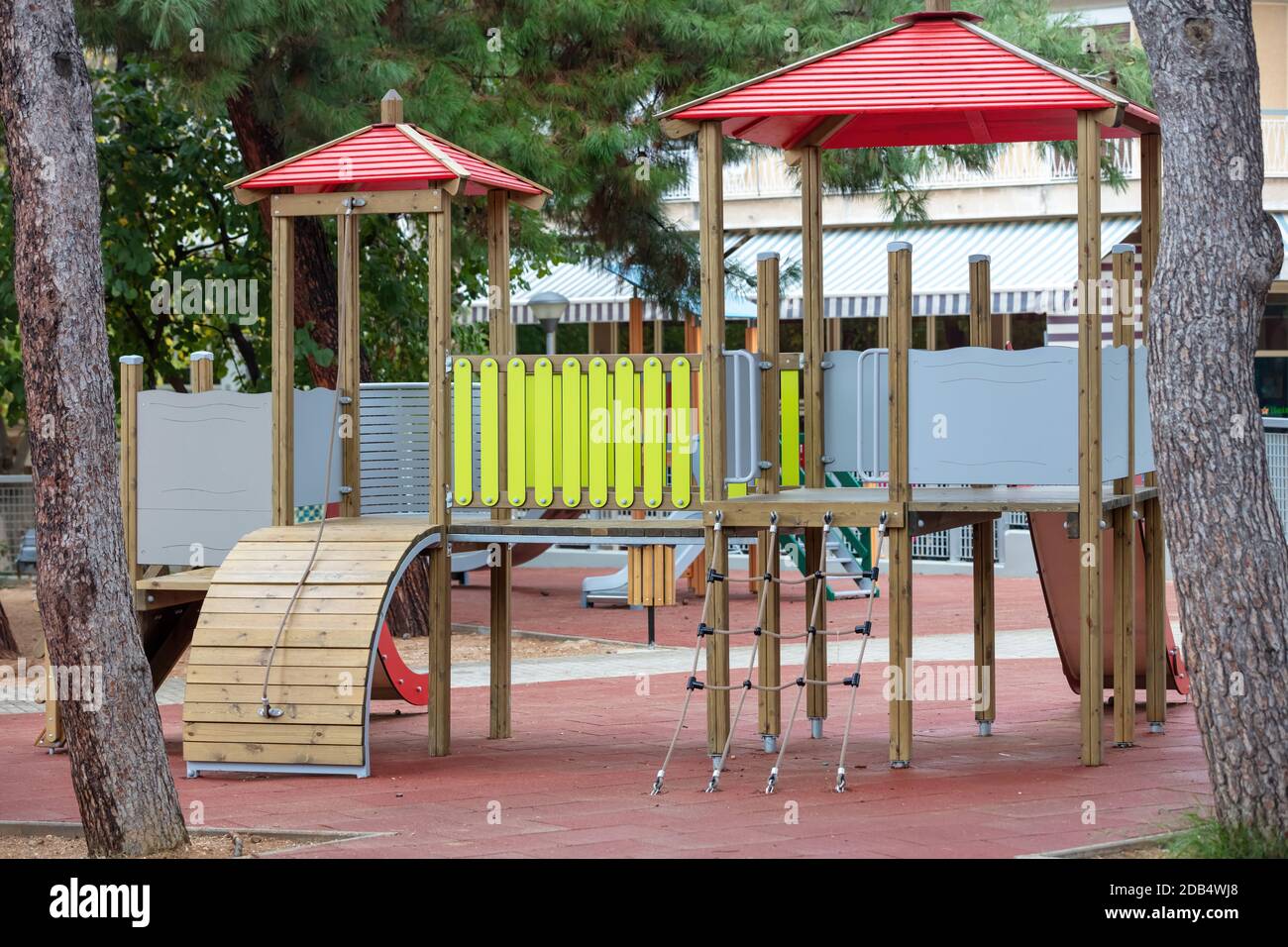 Modern playground with colorful wooden slides and ladders located near tree trunks. Kids entertaiment place Stock Photo