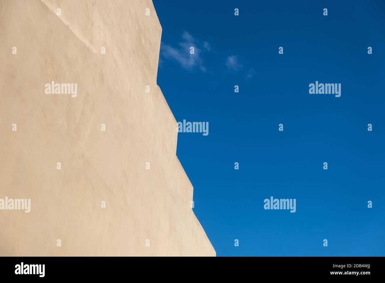 Building wall beige yellow color with zigzag edge located against bright blue sky background, copy space, template Stock Photo