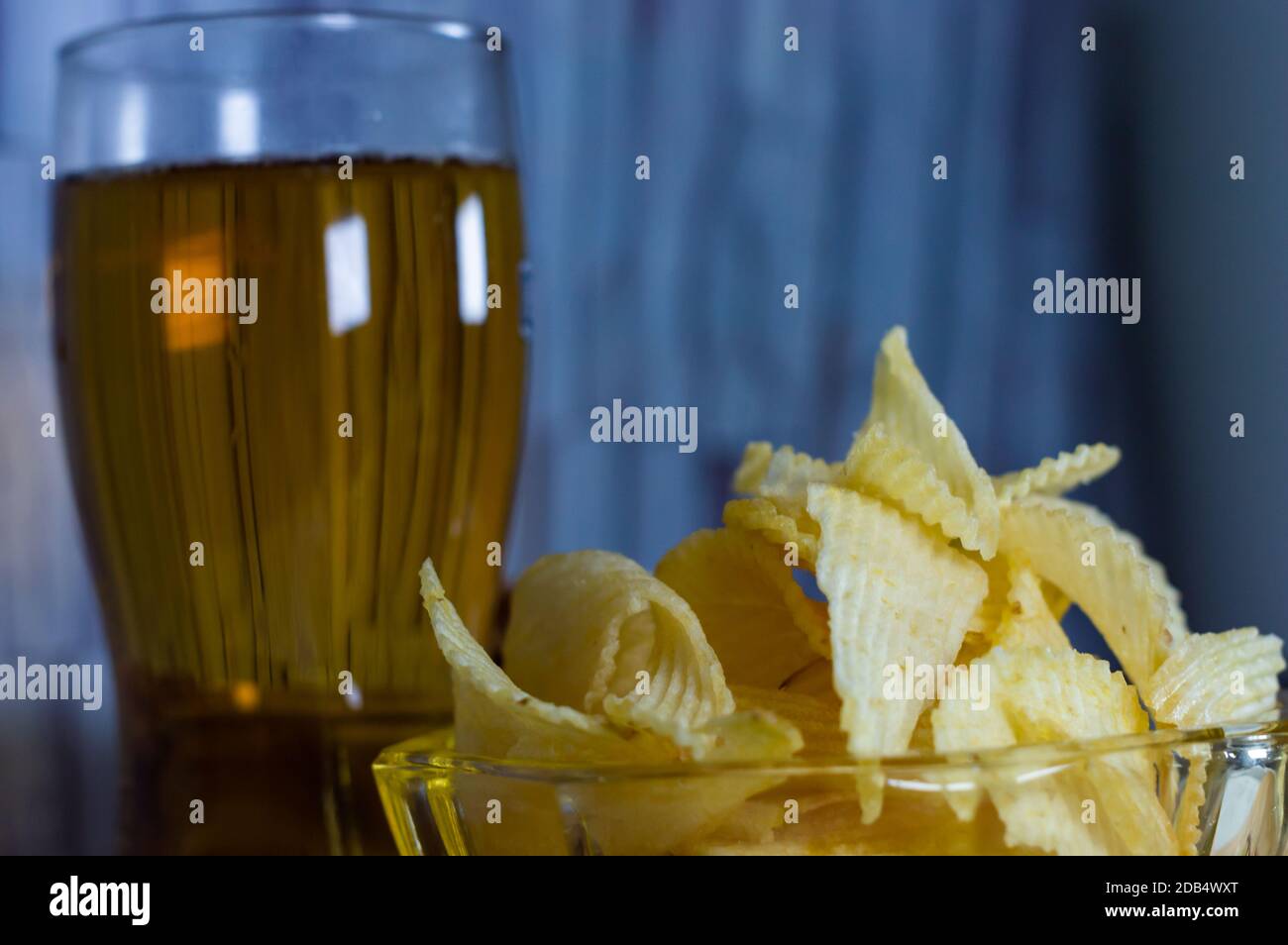Cold beer and wavy potato chips in a bowl on a wood table - empty copy space area Stock Photo