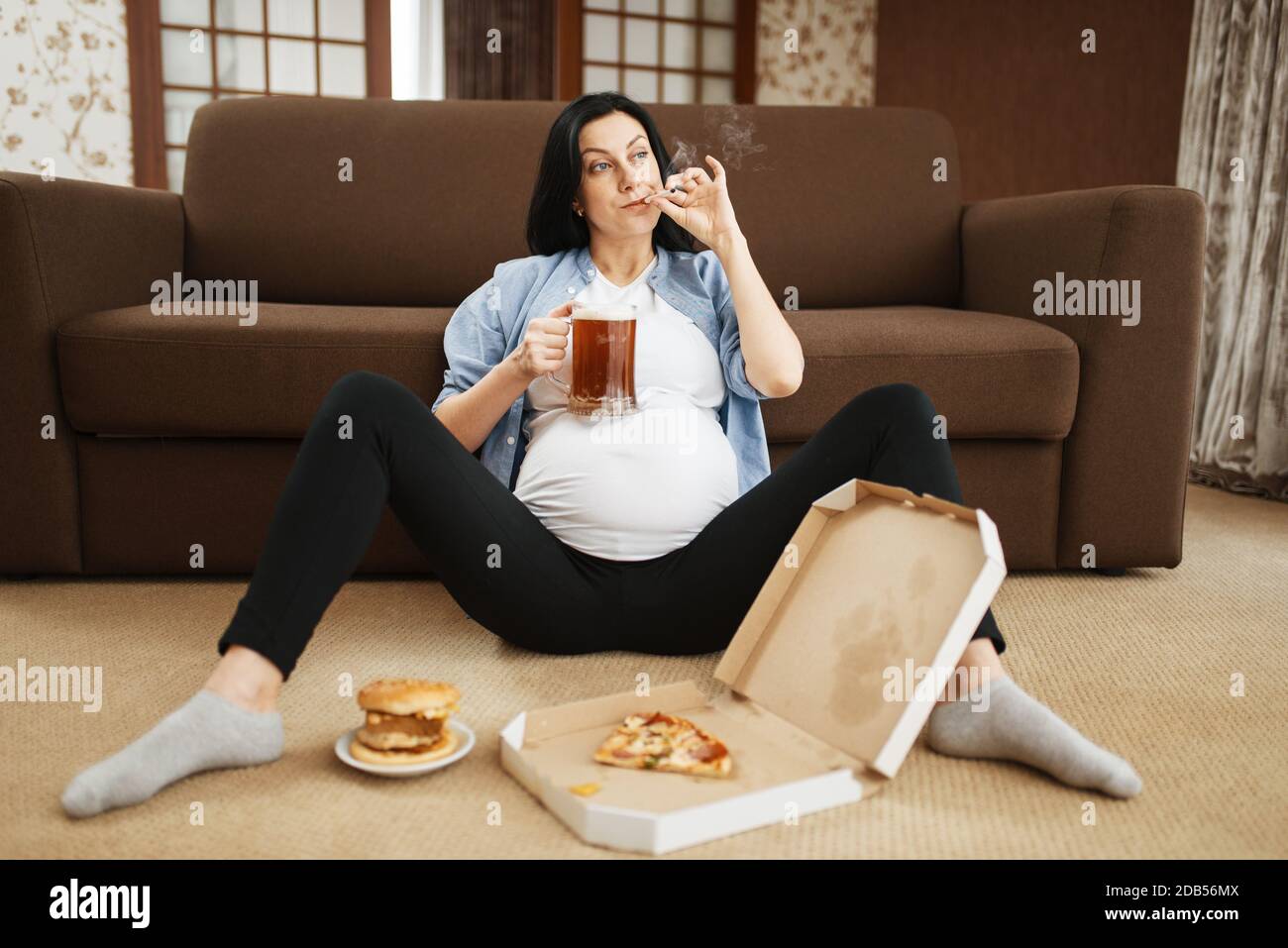 Pregnant woman with belly smoking and drinks beer at home. Pregnancy