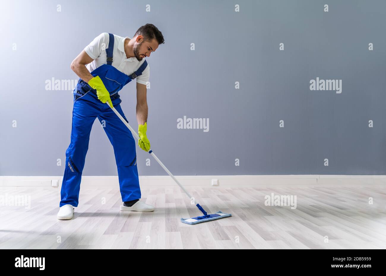 Worker Mopping Floor With Mop In Office Stock Photo