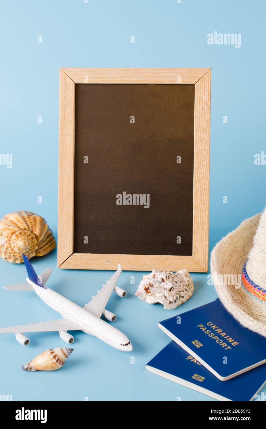 Empty chalkboard with decorative airplane, passports and seashells . Summer travel concept. Top view, flat lay. Copy Space. Mock up. Stock Photo