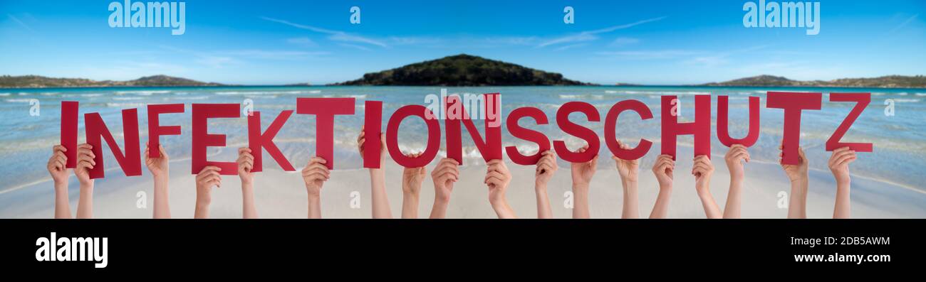 People Hands Holding Red German Word Infektionsschutz Means Infection Protection. Ocean And Beach As Background Stock Photo