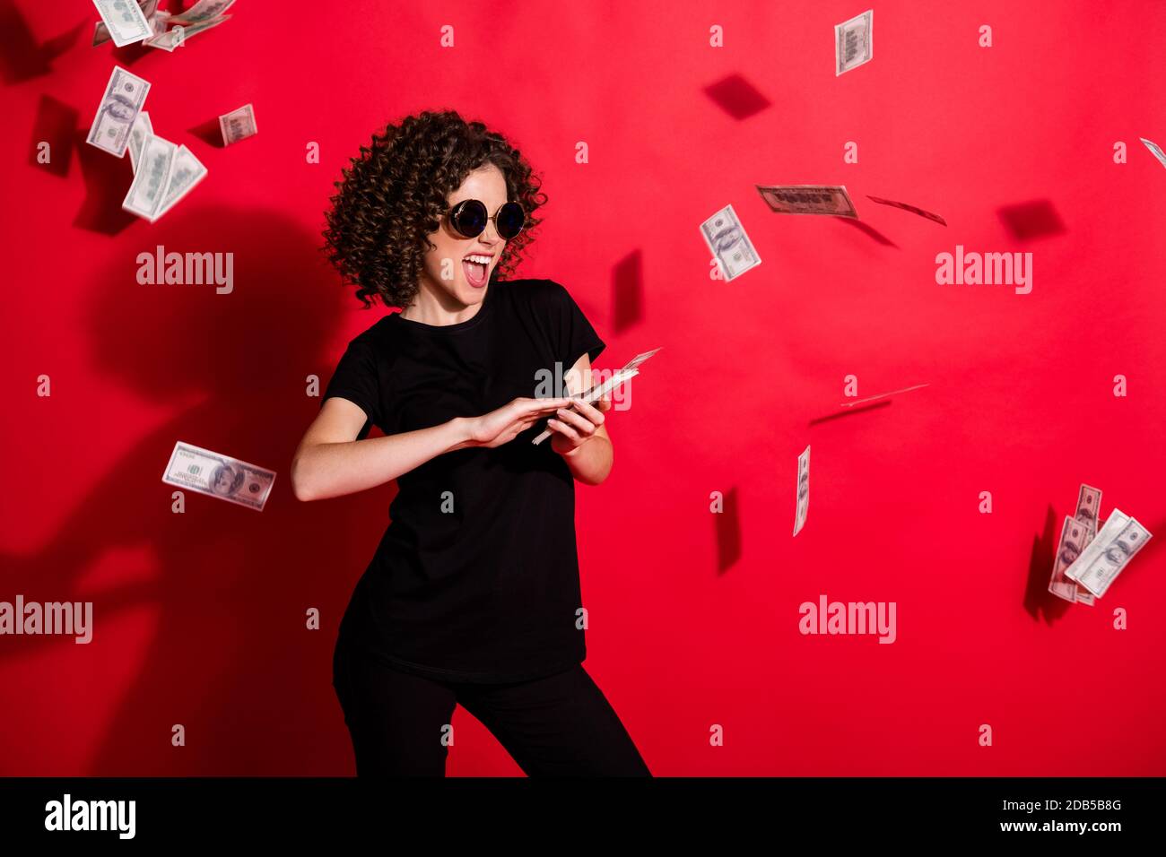 Photo portrait of woman throwing money in air isolated on vivid red