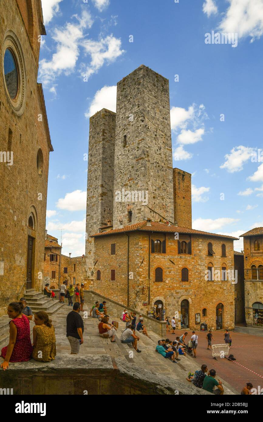 People and tourists on the staircase of the Duomo with the Torri dei Salvucci twin towers in the medieval town of San Gimignano, Siena, Tuscany, Italy Stock Photo