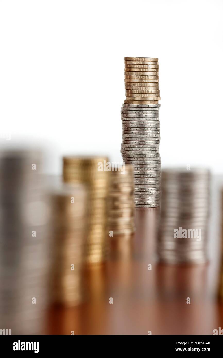 Flat-angled view of stacked euro coins on smooth wooden background. Focus on the last stack with aperture F8. Stock Photo