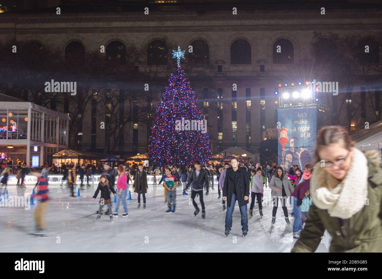 People Skating on the Ice Rink in Bryant Park in Manhattan on Christmas Day. Impressive Christmas Tree in the Background. New York City, USA Stock Photo
