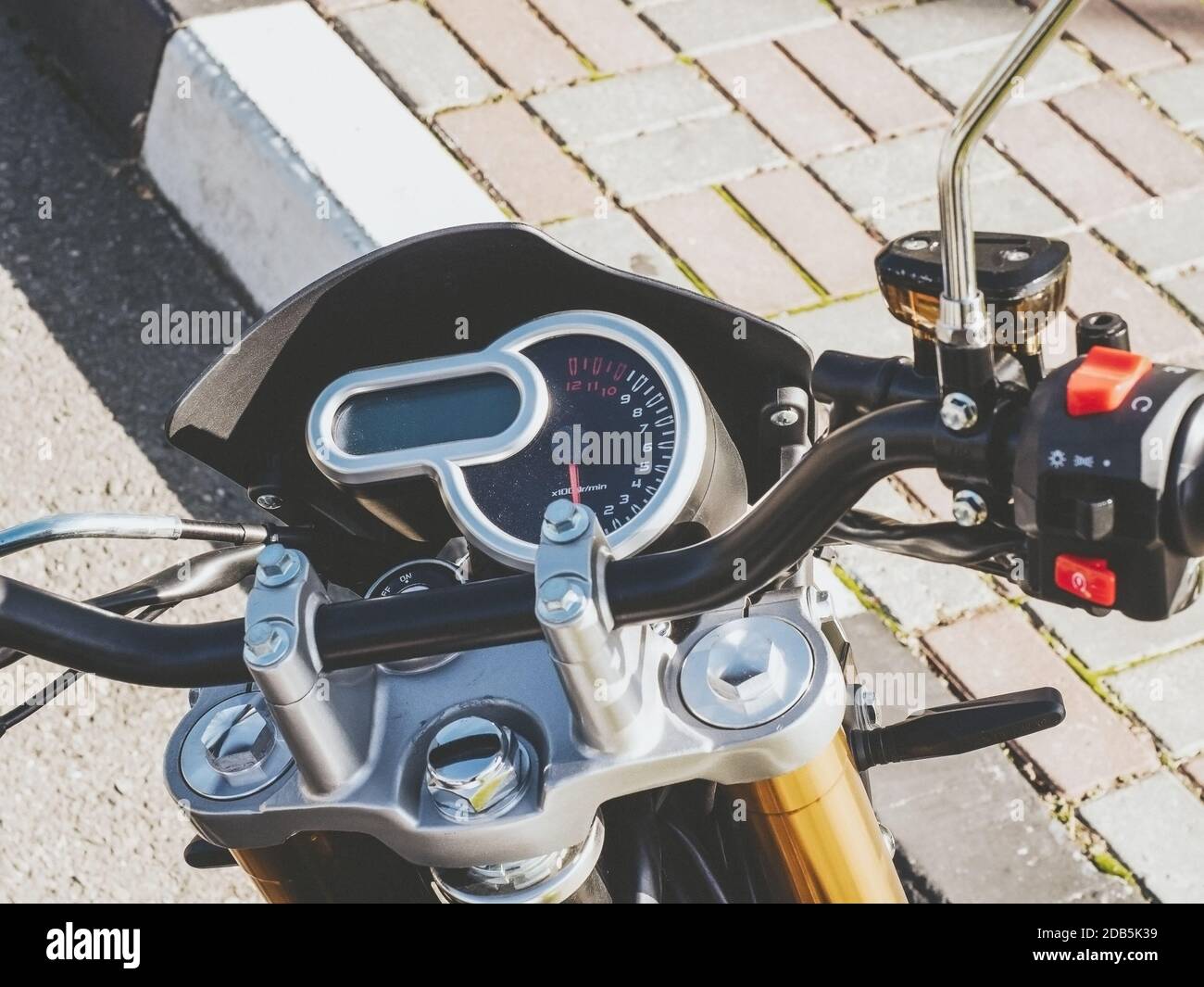 Fragment of a motorcycle steering wheel with a round speedometer outdoors. Closeup photo with filter Stock Photo