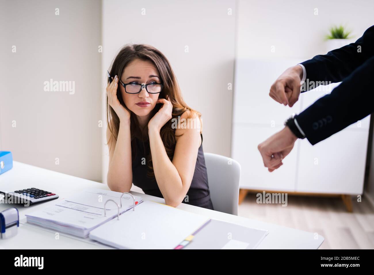 Angry Boss Pointing On Wrist Watch While Colleague Checking Invoice Stock Photo