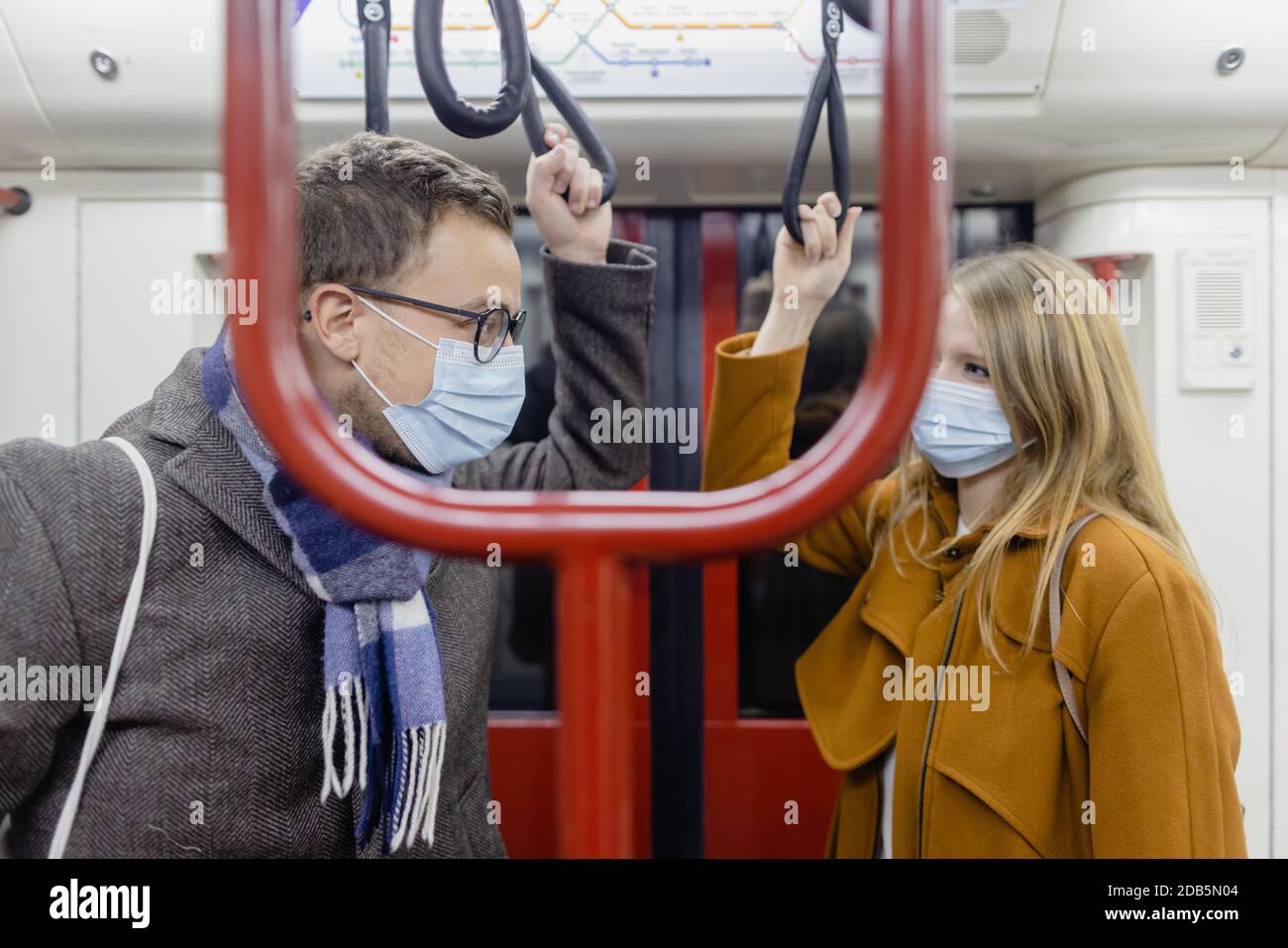 Flirty couple with covid 19 face masks in a train Stock Photo