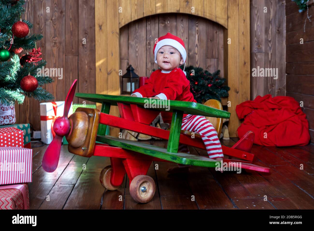 little boy in Santa costume on a wooden plane Stock Photo