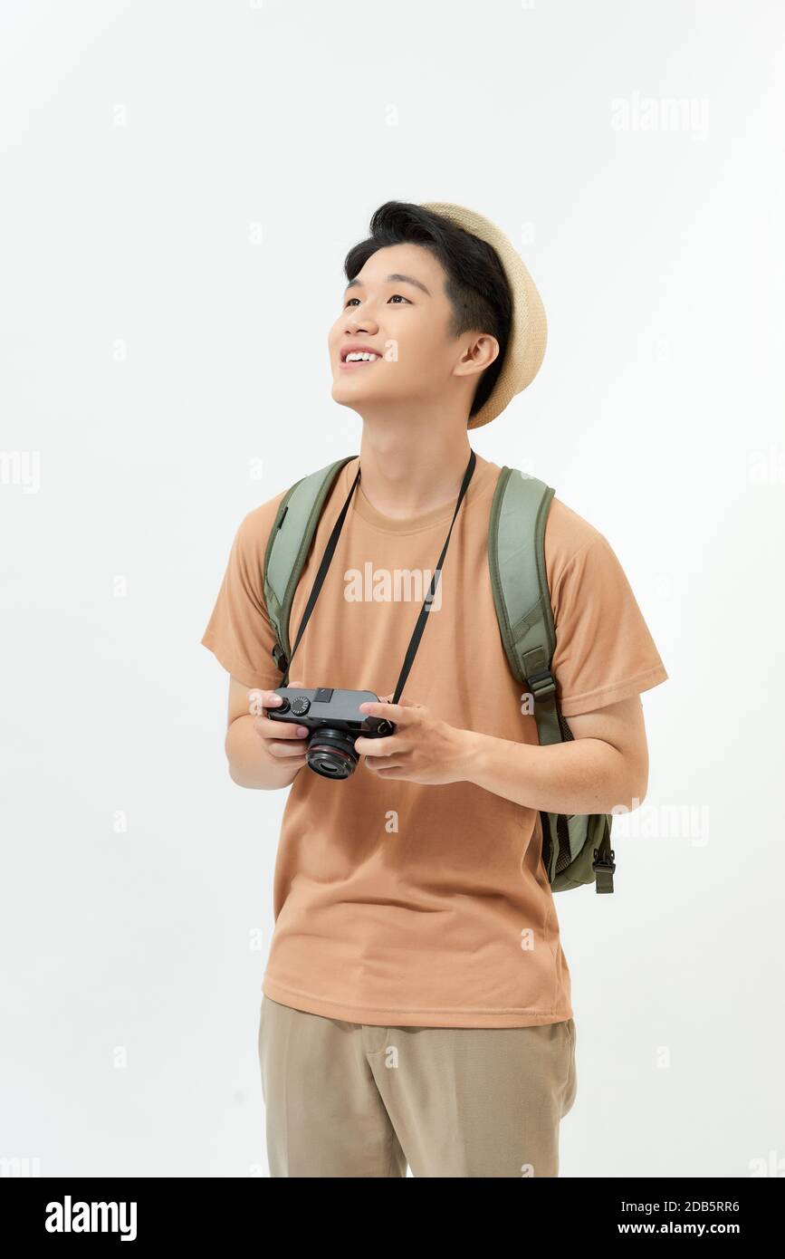 Traveler and photographer. Studio portrait of handsome young man holding photocamera taking photo. Stock Photo