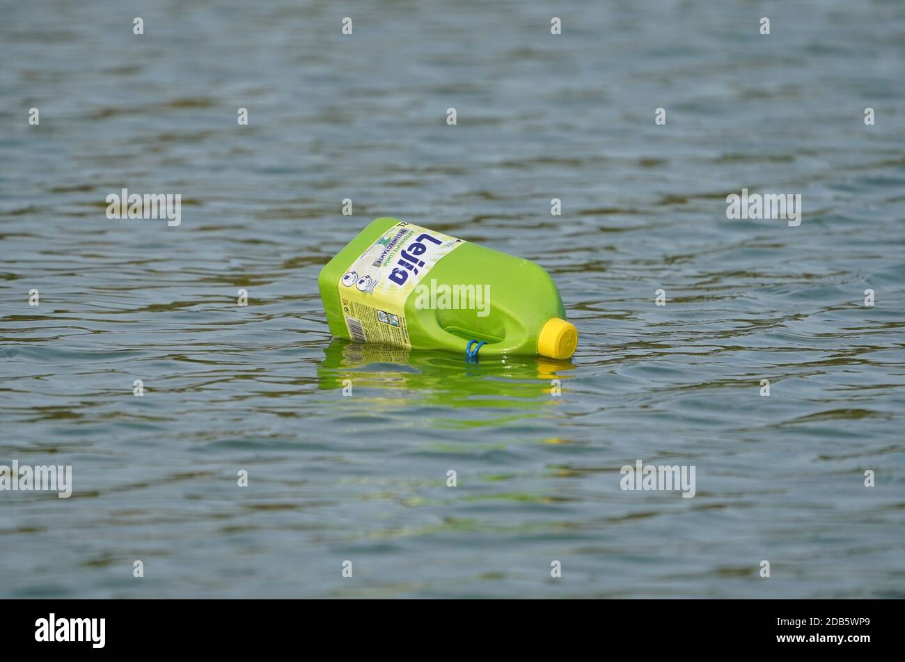Plastic bottle of bleach floating in a river on water surface, pollution. Spain. Stock Photo