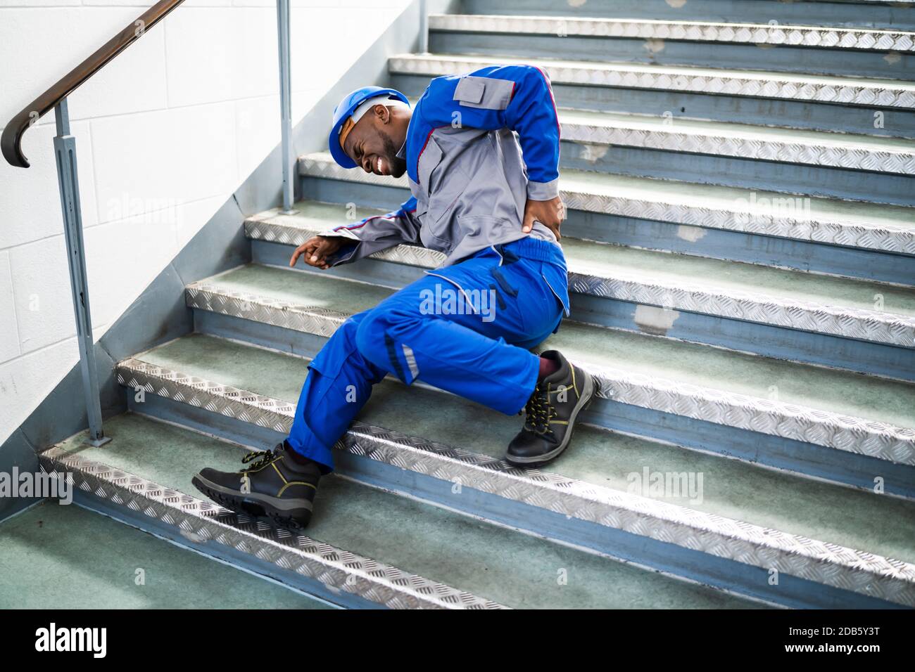 Worker Man Lying On Staircase After Slip And Fall Accident Stock Photo