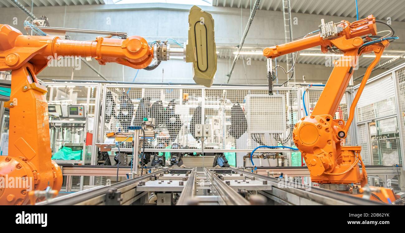 orange robot arms on the production line. controlled by a computer with artificial intelligence. Stock Photo
